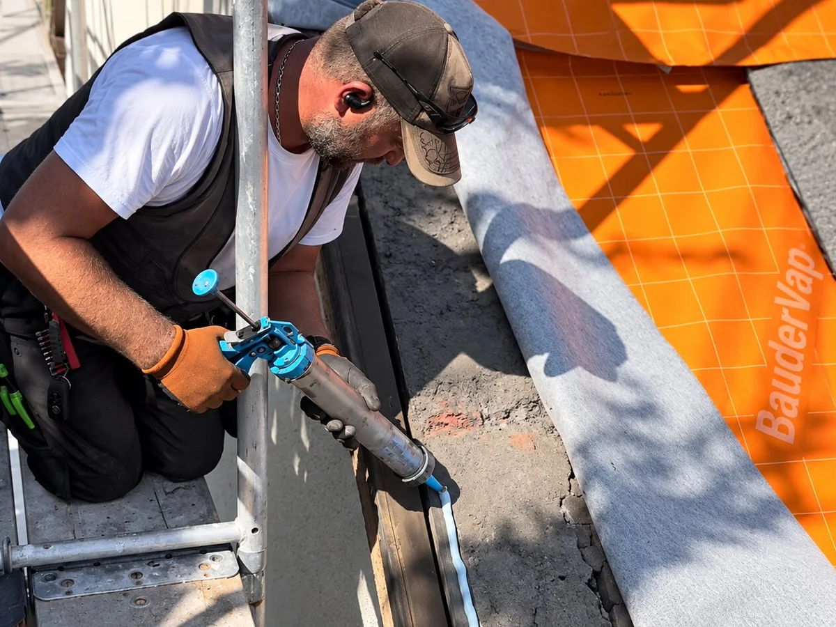 Dachdecker verklebt Dampfsperre mit Kartuschenpistole