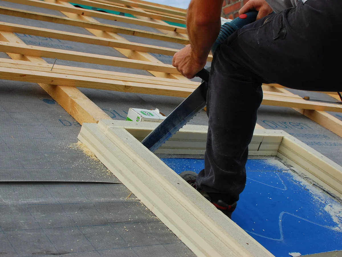 Bauarbeiter schneidet mit einer Säbelsäge Dachdämmmaterial passgenau zu