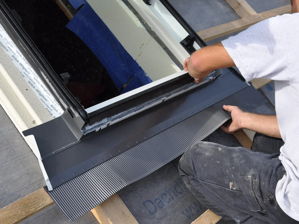 Dachdecker montiert das Anschlussblech (Eindeckrahmen) an einem Dachfenster